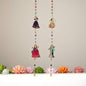 Decorative hanging with colorful beads and small figurines on a neutral background