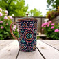 Decorative mug with floral pattern on a wooden table outdoors