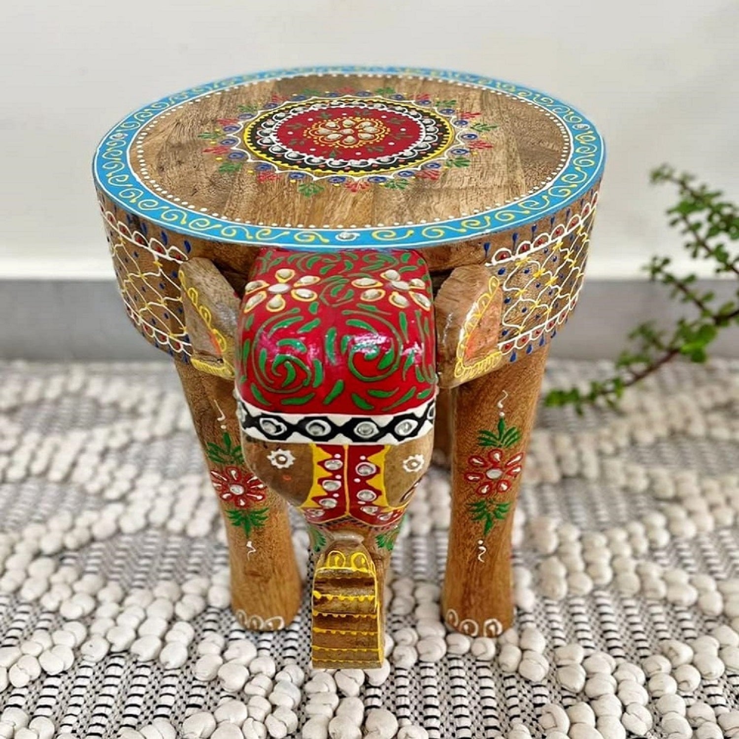 A hand-crafted wooden elephant stool with a hand-painted design, featuring floral patterns and global style accents on a 12-inch tall stool.