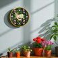 Decorative wall piece with cows and flowers on a light blue wall, below which are potted plants.