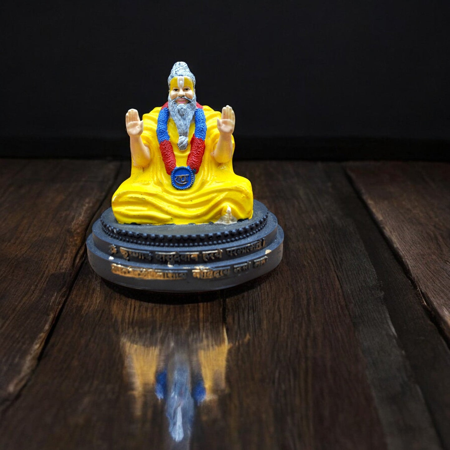 Statue of a seated figure in yellow robes on a dark wooden surface