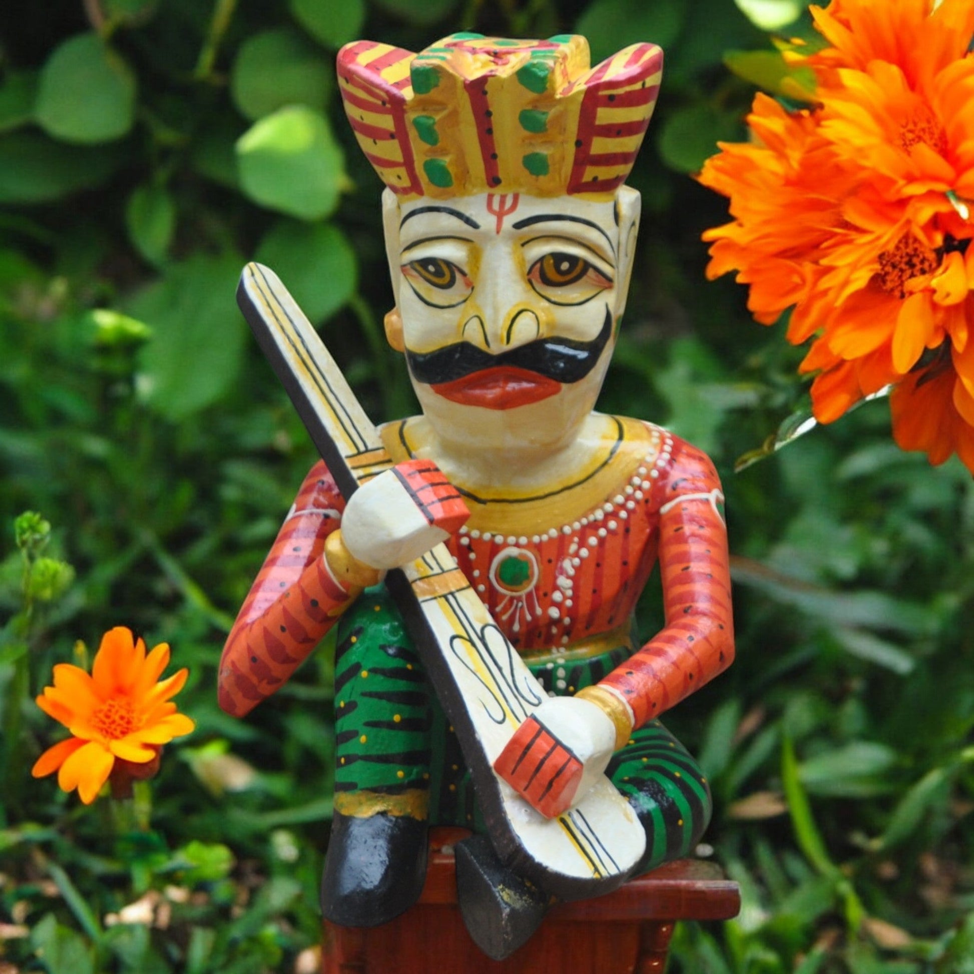 Colorful figurine of a traditional musician with a guitar, set against a natural background with orange flowers.