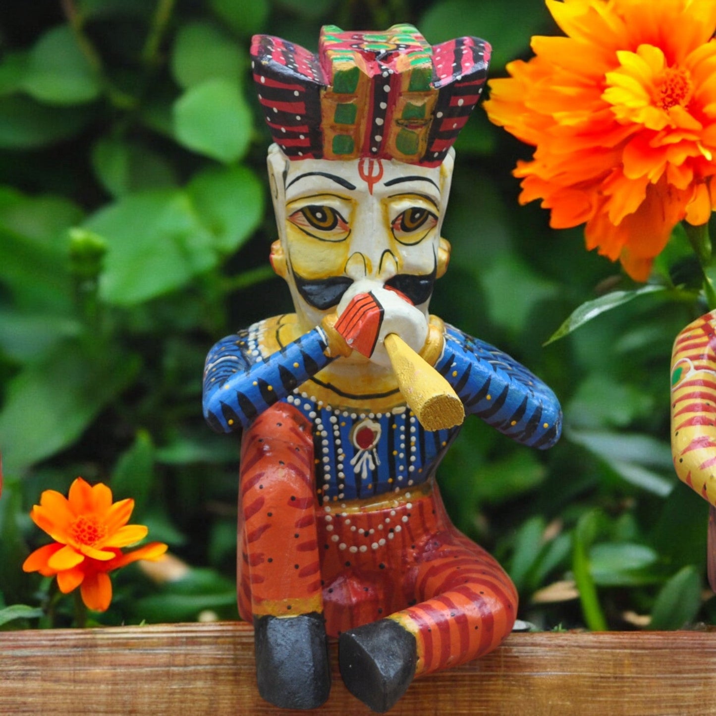 Colorful figurine of a character playing a flute with orange flowers in the background