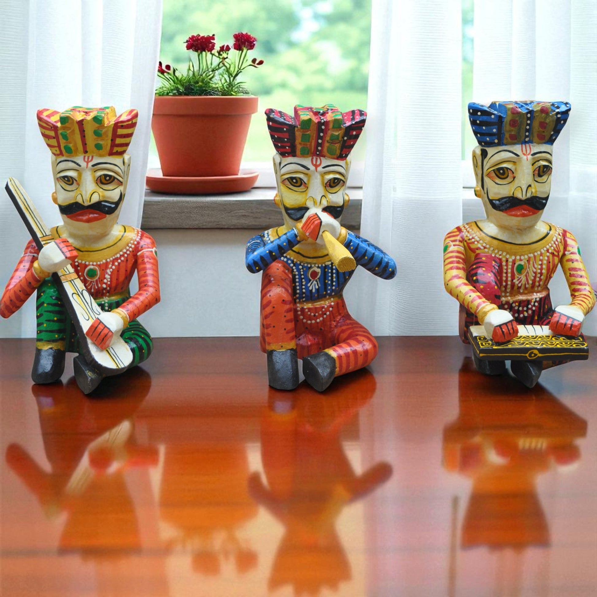 Three colorful figurines on a reflective surface with a plant in the background.