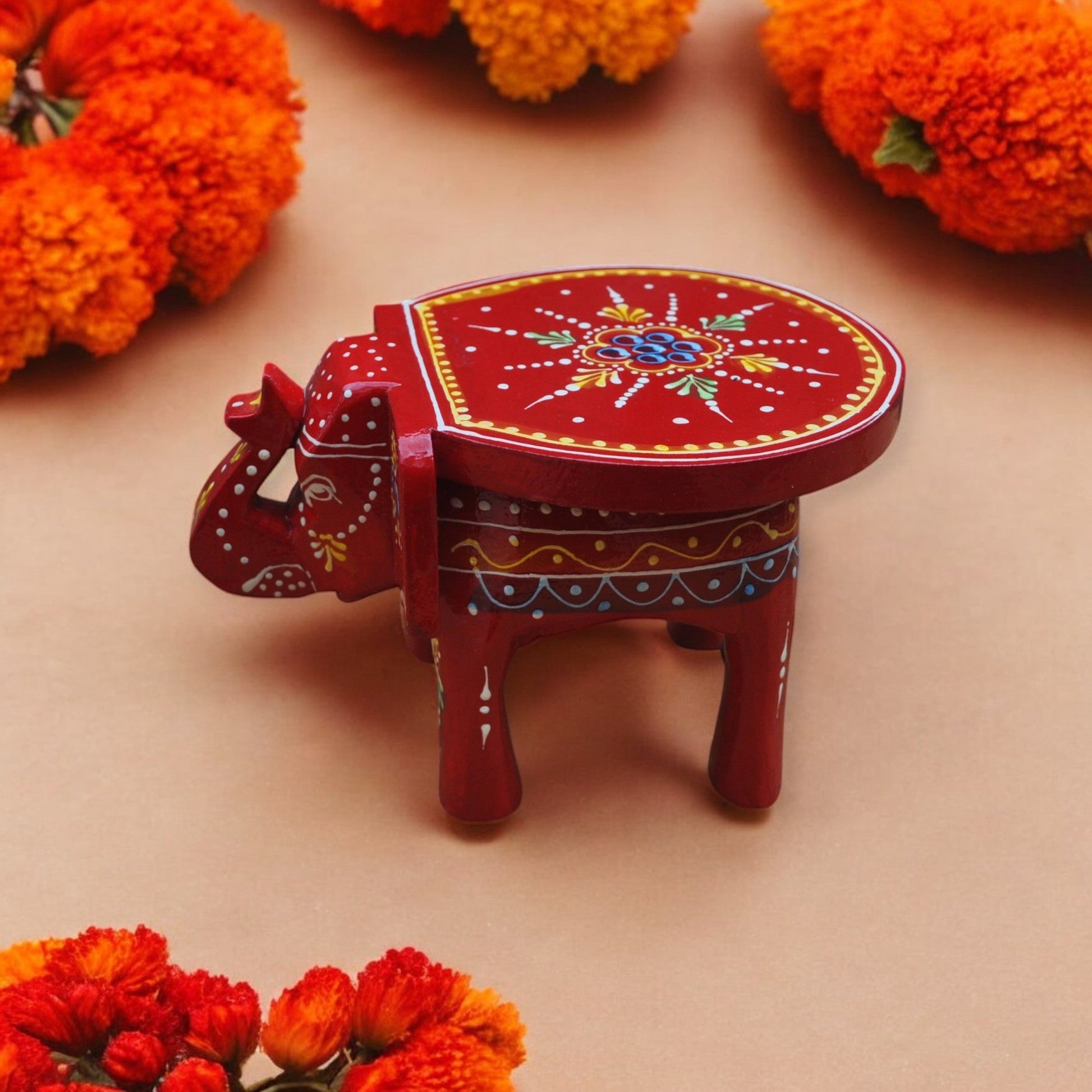 Decorative red elephant with floral patterns on a beige background with orange flowers.