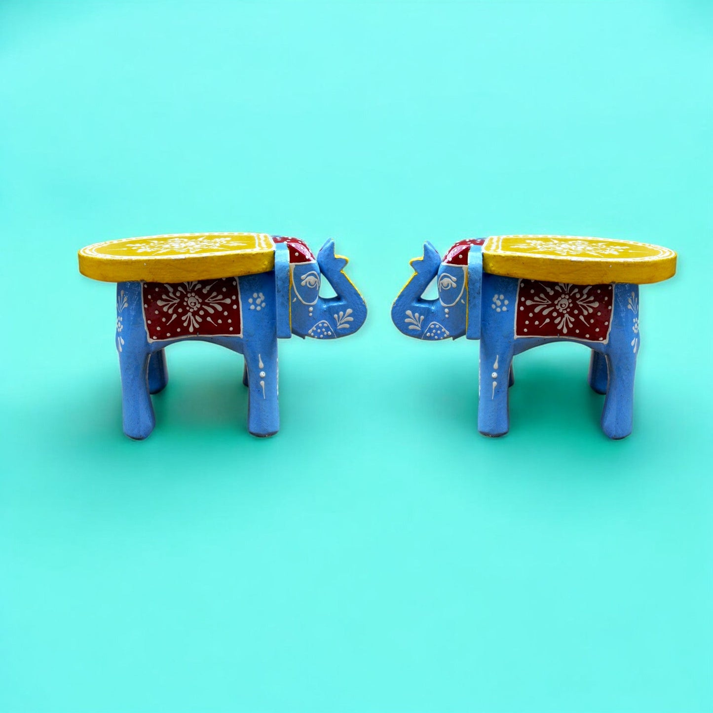 Two colorful elephant-shaped stools on a turquoise background