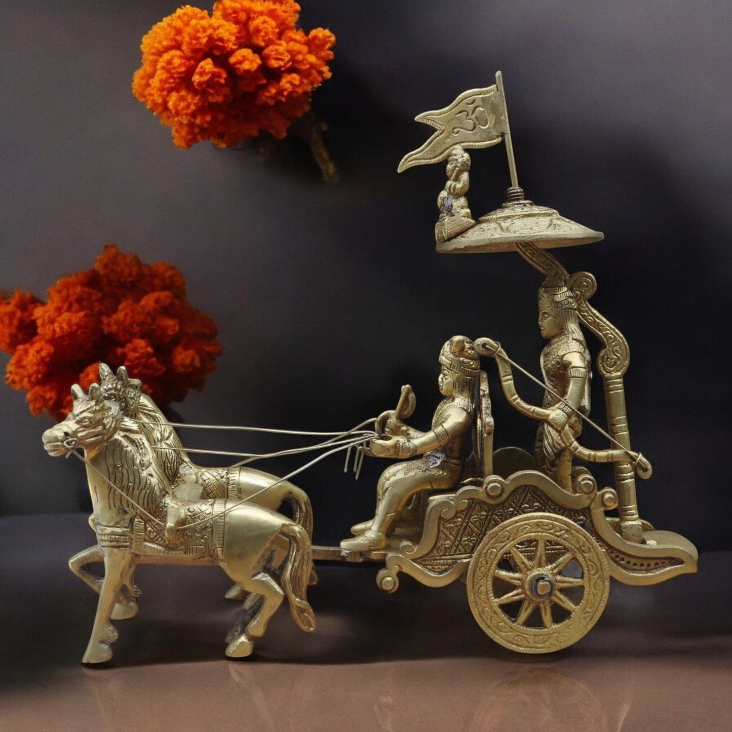 Bronze chariot sculpture with horses and figures, against a dark background.