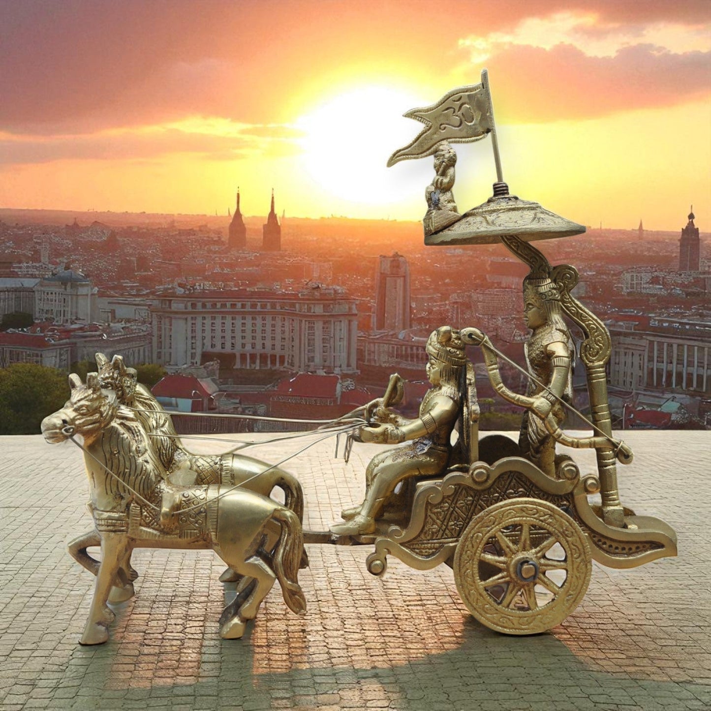 Bronze chariot with horses and figures against a cityscape at sunset