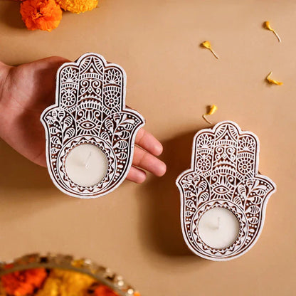 Decorative Hamsa hand candle holders with candles on a beige background.